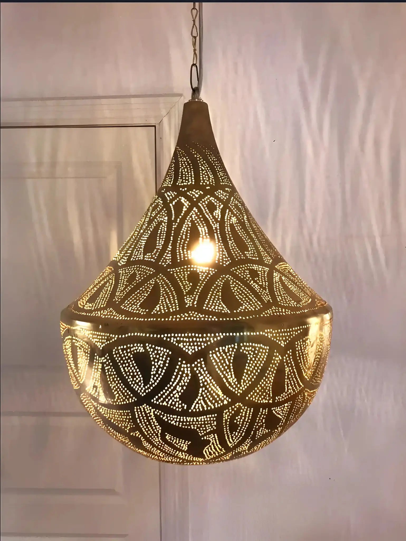 Orientalisk hänglampa i silver med perforerat mönster och varm belysning inomhus